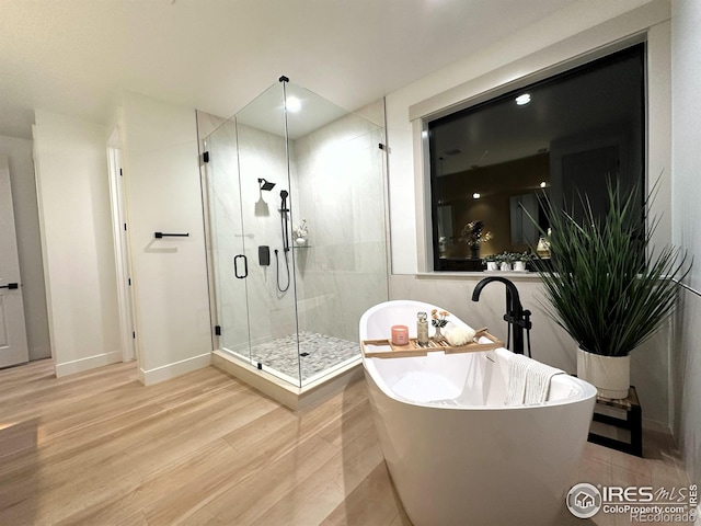 bathroom with wood-type flooring and shower with separate bathtub