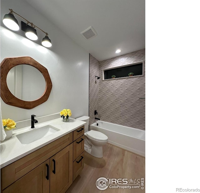 full bathroom featuring toilet, tiled shower / bath, hardwood / wood-style floors, and vanity