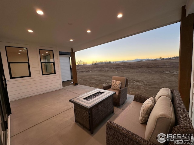 patio terrace at dusk with an outdoor living space with a fire pit