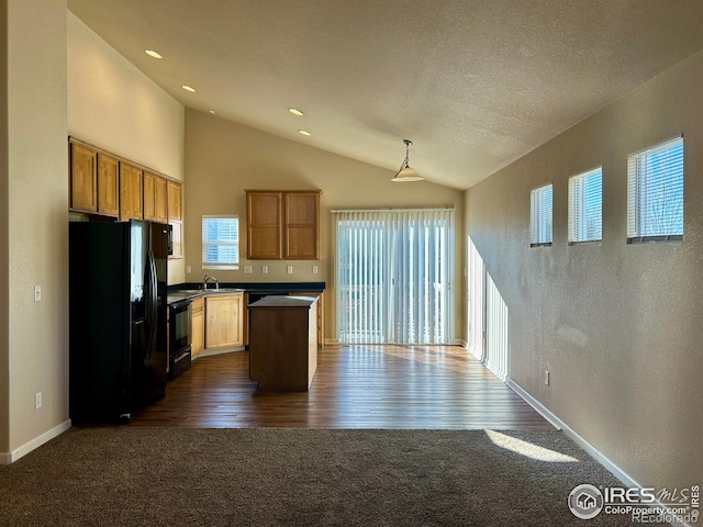 kitchen featuring dark wood-type flooring, black appliances, sink, hanging light fixtures, and a textured ceiling