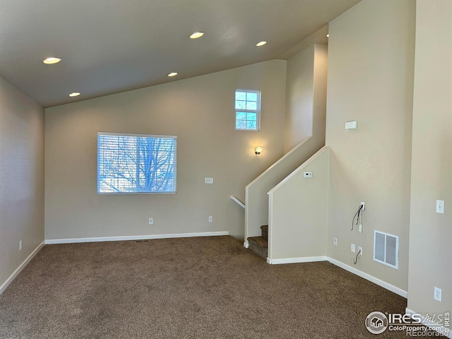 unfurnished living room with lofted ceiling and dark colored carpet