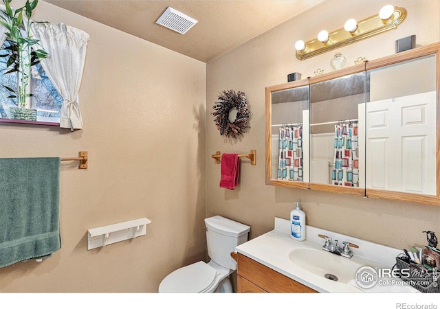 bathroom with a shower with shower curtain, a textured ceiling, vanity, and toilet