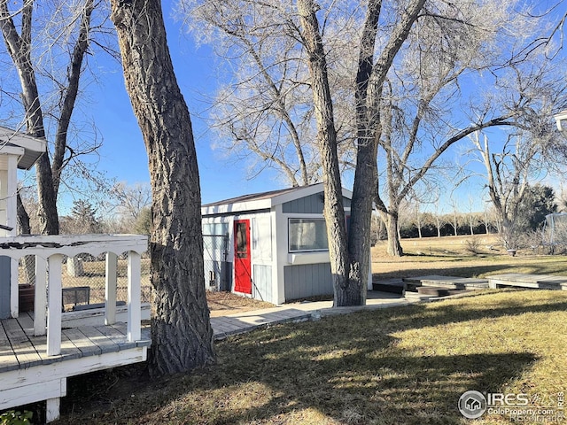 view of property exterior with a yard, a deck, and a storage unit