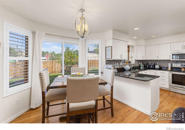 kitchen with stainless steel electric stove, white cabinetry, hanging light fixtures, and an inviting chandelier