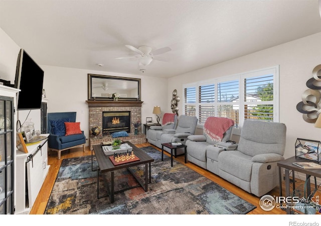 living room featuring a fireplace, ceiling fan, and dark wood-type flooring