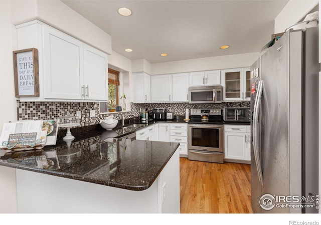 kitchen featuring kitchen peninsula, appliances with stainless steel finishes, sink, white cabinets, and light hardwood / wood-style floors