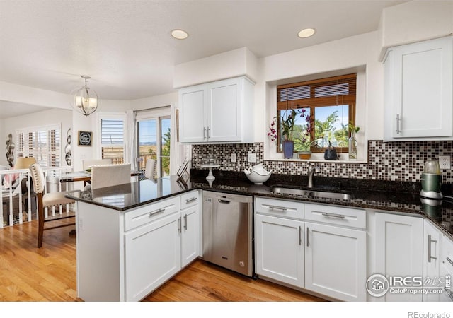 kitchen featuring stainless steel dishwasher, kitchen peninsula, decorative light fixtures, white cabinets, and light wood-type flooring