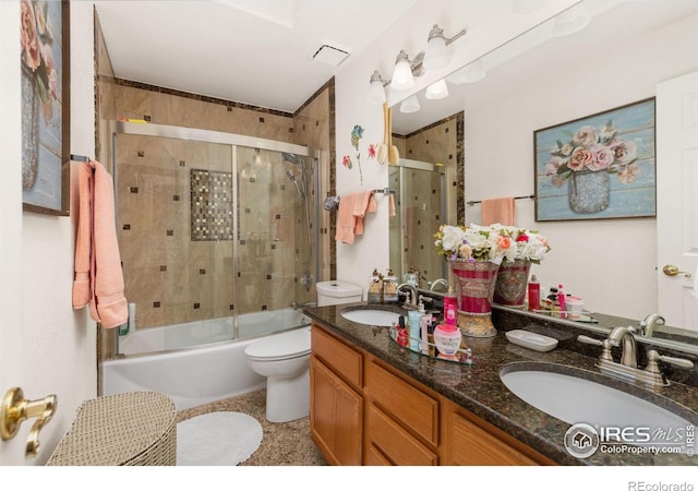 full bathroom with combined bath / shower with glass door, vanity, and toilet