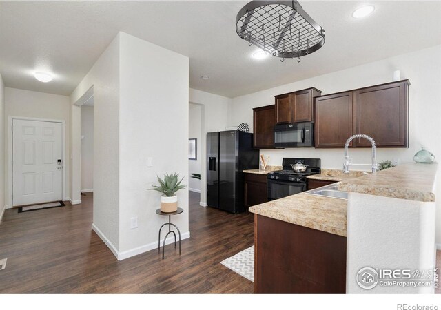 kitchen featuring kitchen peninsula, dark hardwood / wood-style flooring, dark brown cabinetry, sink, and black appliances