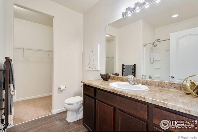 bathroom featuring a shower, vanity, hardwood / wood-style flooring, and toilet