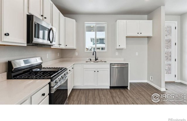 kitchen featuring stainless steel appliances, sink, white cabinets, and light hardwood / wood-style flooring