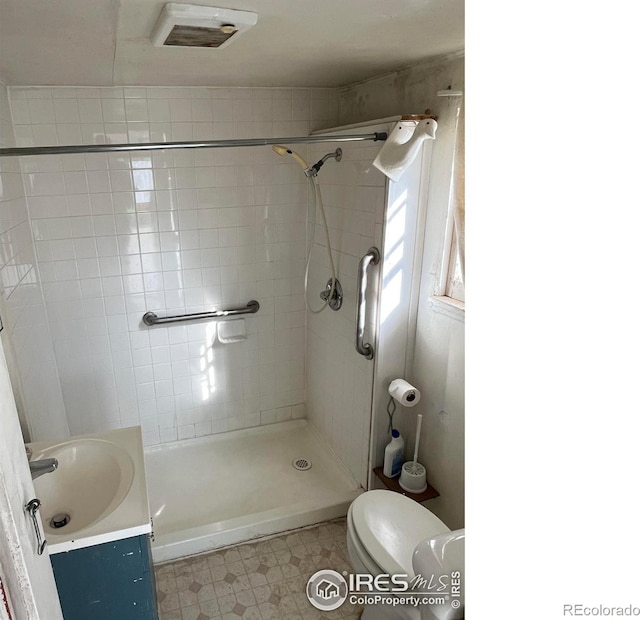 bathroom featuring a tile shower, vanity, and toilet