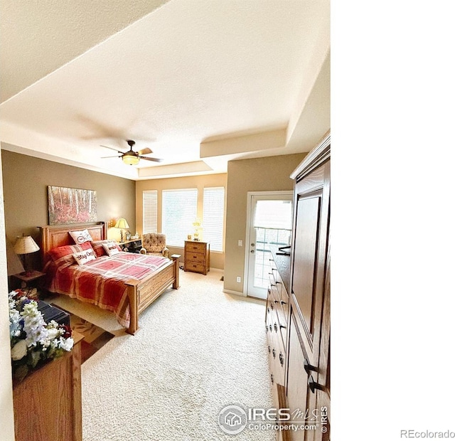 bedroom featuring light carpet, a raised ceiling, ceiling fan, access to exterior, and a textured ceiling