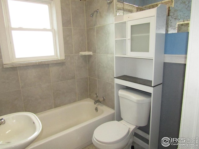 full bathroom featuring sink, tiled shower / bath combo, and toilet