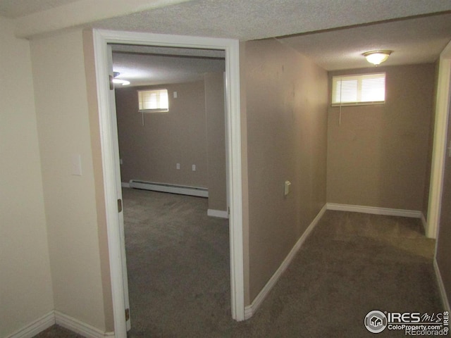 basement with carpet flooring, a textured ceiling, and a baseboard heating unit