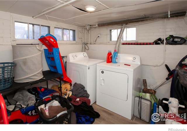 clothes washing area featuring hardwood / wood-style flooring, plenty of natural light, and independent washer and dryer