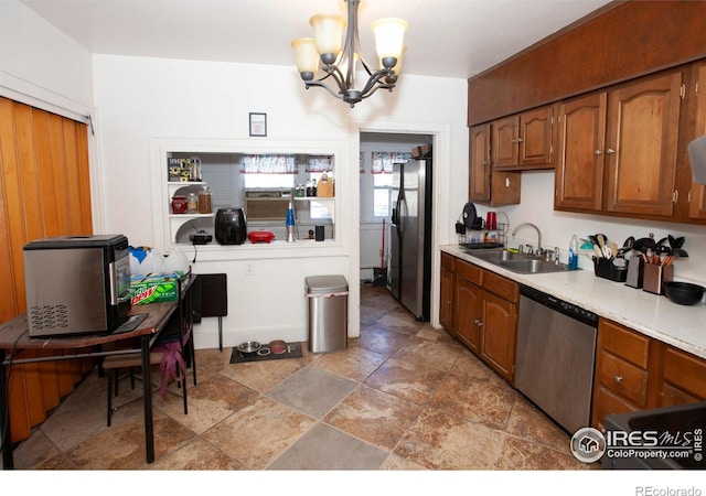 kitchen featuring sink, pendant lighting, stainless steel appliances, and a notable chandelier