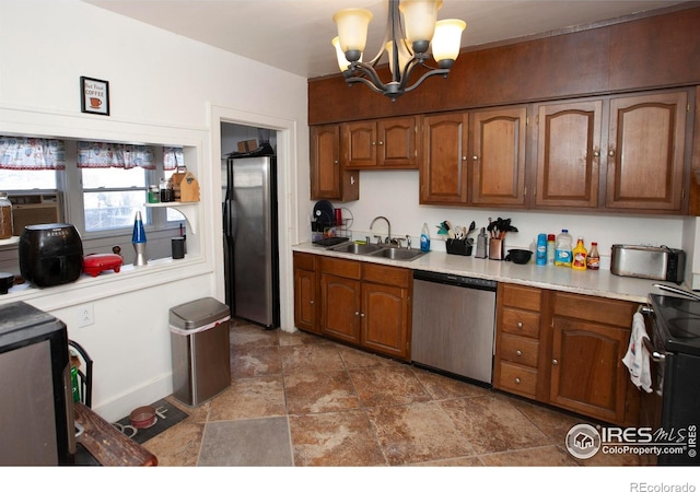 kitchen with appliances with stainless steel finishes, an inviting chandelier, pendant lighting, and sink