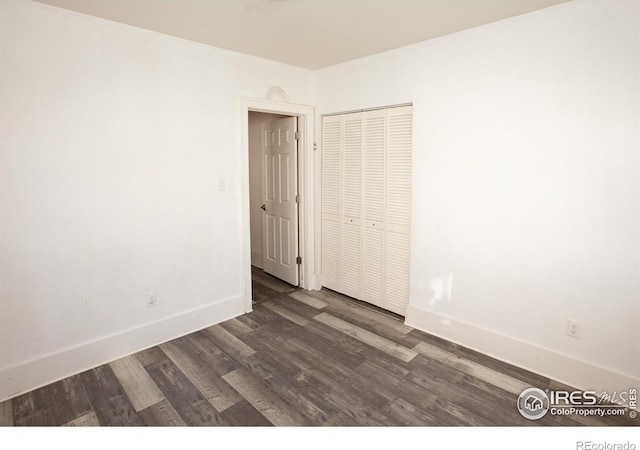 unfurnished bedroom featuring dark hardwood / wood-style flooring and a closet