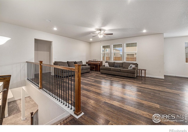 living room featuring a textured ceiling, dark hardwood / wood-style flooring, and ceiling fan