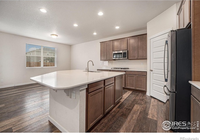 kitchen featuring a center island with sink, sink, dark hardwood / wood-style flooring, and stainless steel appliances