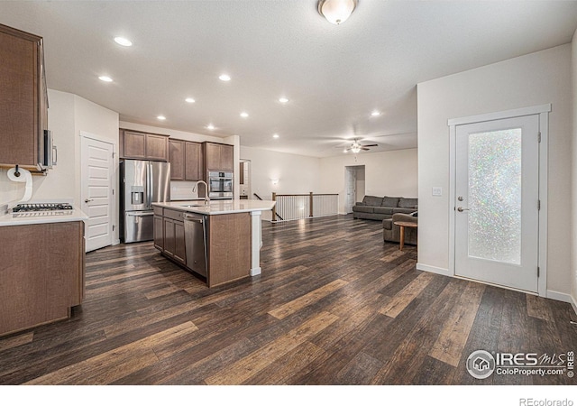 kitchen featuring stainless steel appliances, ceiling fan, sink, dark hardwood / wood-style floors, and an island with sink