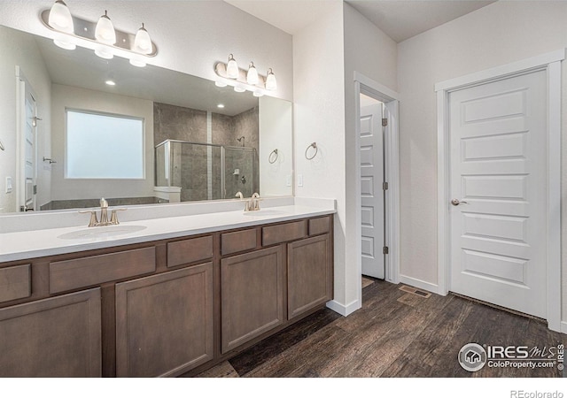 bathroom with hardwood / wood-style floors, vanity, and a shower with door