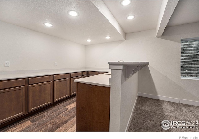 bar featuring a textured ceiling, dark brown cabinetry, and dark hardwood / wood-style floors