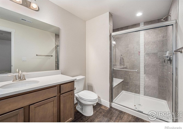 bathroom featuring vanity, toilet, wood-type flooring, and a shower with door