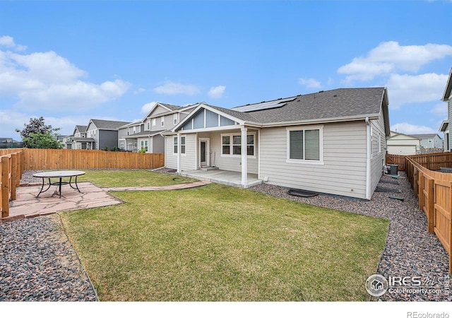 rear view of property with solar panels, a patio, and a yard