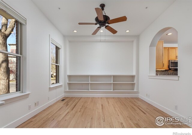 empty room featuring ceiling fan, plenty of natural light, and light wood-type flooring