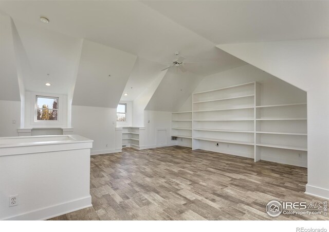 bonus room featuring ceiling fan, lofted ceiling, light hardwood / wood-style floors, and built in shelves