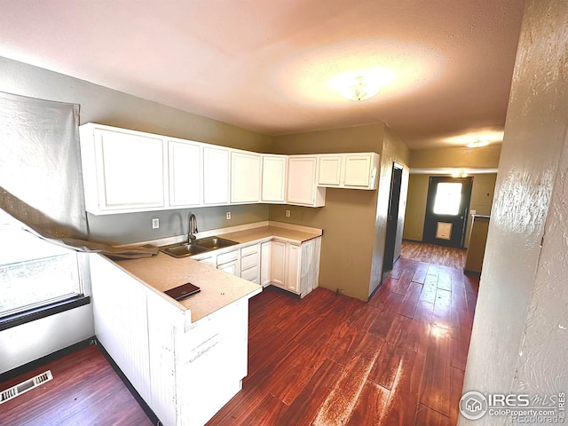 kitchen featuring kitchen peninsula, white cabinetry, dark wood-type flooring, and sink