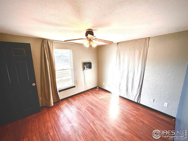 unfurnished room with a textured ceiling, hardwood / wood-style flooring, a wall unit AC, and ceiling fan