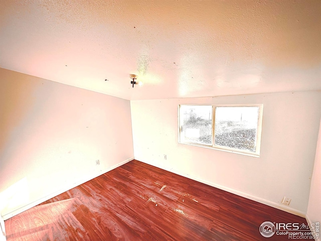 empty room with wood-type flooring and a textured ceiling