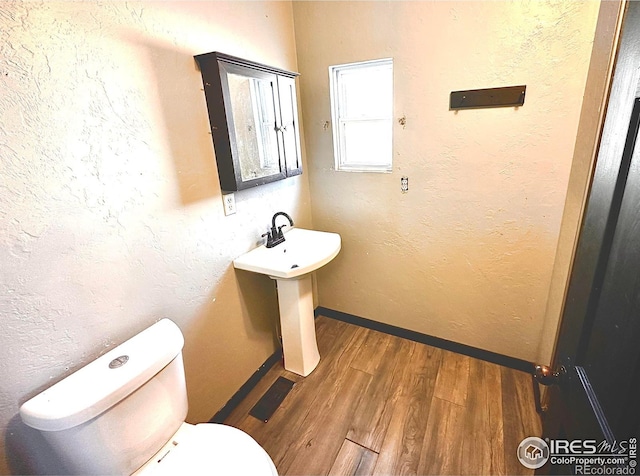 bathroom with hardwood / wood-style flooring and toilet