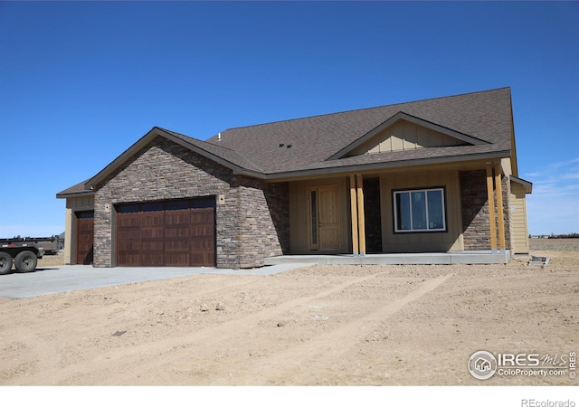 view of front of home featuring stone siding, board and batten siding, an attached garage, and a shingled roof