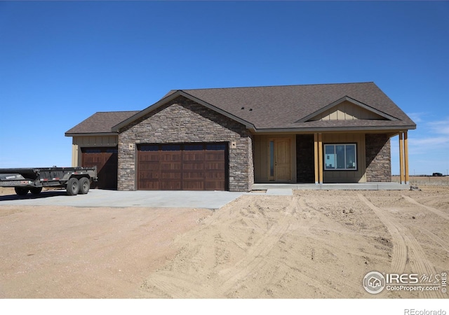 view of front of property with a garage, stone siding, board and batten siding, and dirt driveway