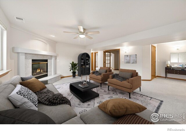 living room featuring light colored carpet, ceiling fan, and a tiled fireplace