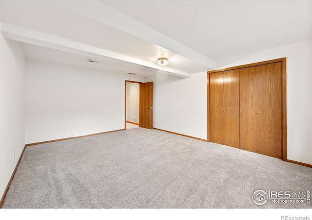 interior space with carpet, beam ceiling, and a closet