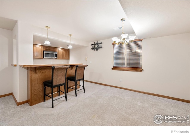 kitchen with a kitchen breakfast bar, kitchen peninsula, light colored carpet, and decorative light fixtures