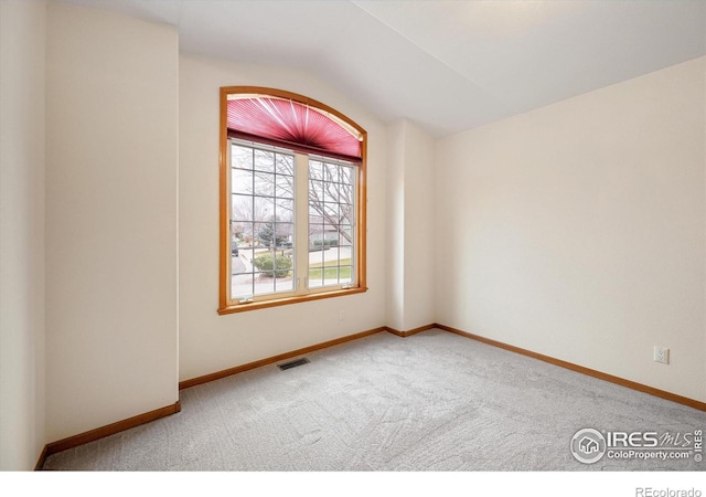 carpeted empty room with vaulted ceiling