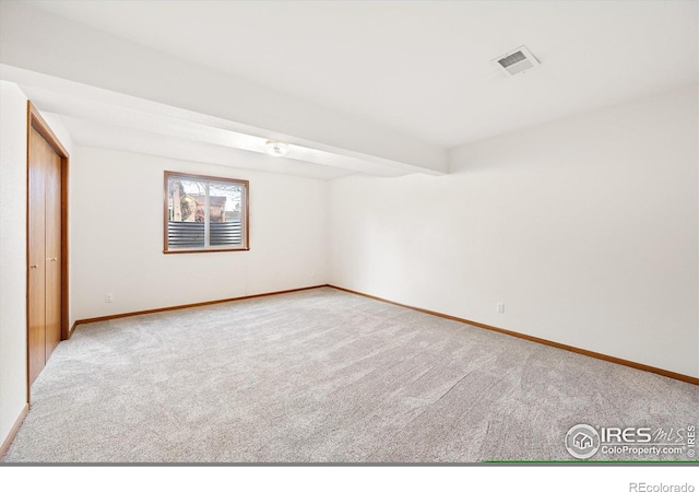 unfurnished room with beam ceiling and light colored carpet