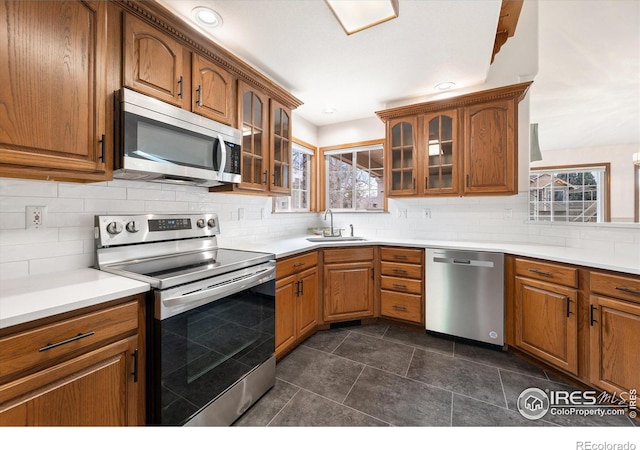 kitchen featuring backsplash, sink, stainless steel appliances, and dark tile patterned flooring