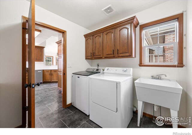 clothes washing area with cabinets, sink, and washing machine and clothes dryer