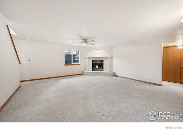 unfurnished living room with a tile fireplace, light colored carpet, and ceiling fan