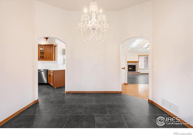 unfurnished room with a fireplace, a towering ceiling, ceiling fan with notable chandelier, and dark wood-type flooring