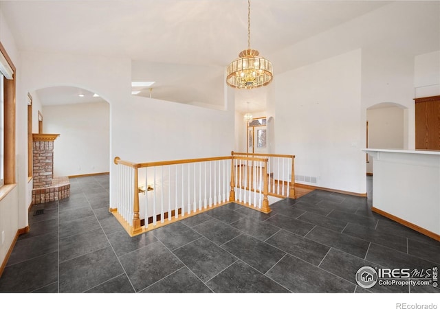 tiled spare room featuring an inviting chandelier, vaulted ceiling, and a brick fireplace