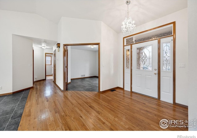 foyer featuring dark hardwood / wood-style flooring, lofted ceiling, and a notable chandelier