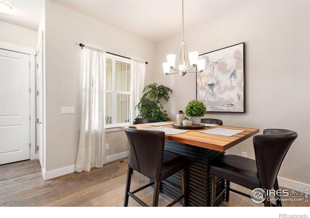 dining space featuring light wood-type flooring and an inviting chandelier